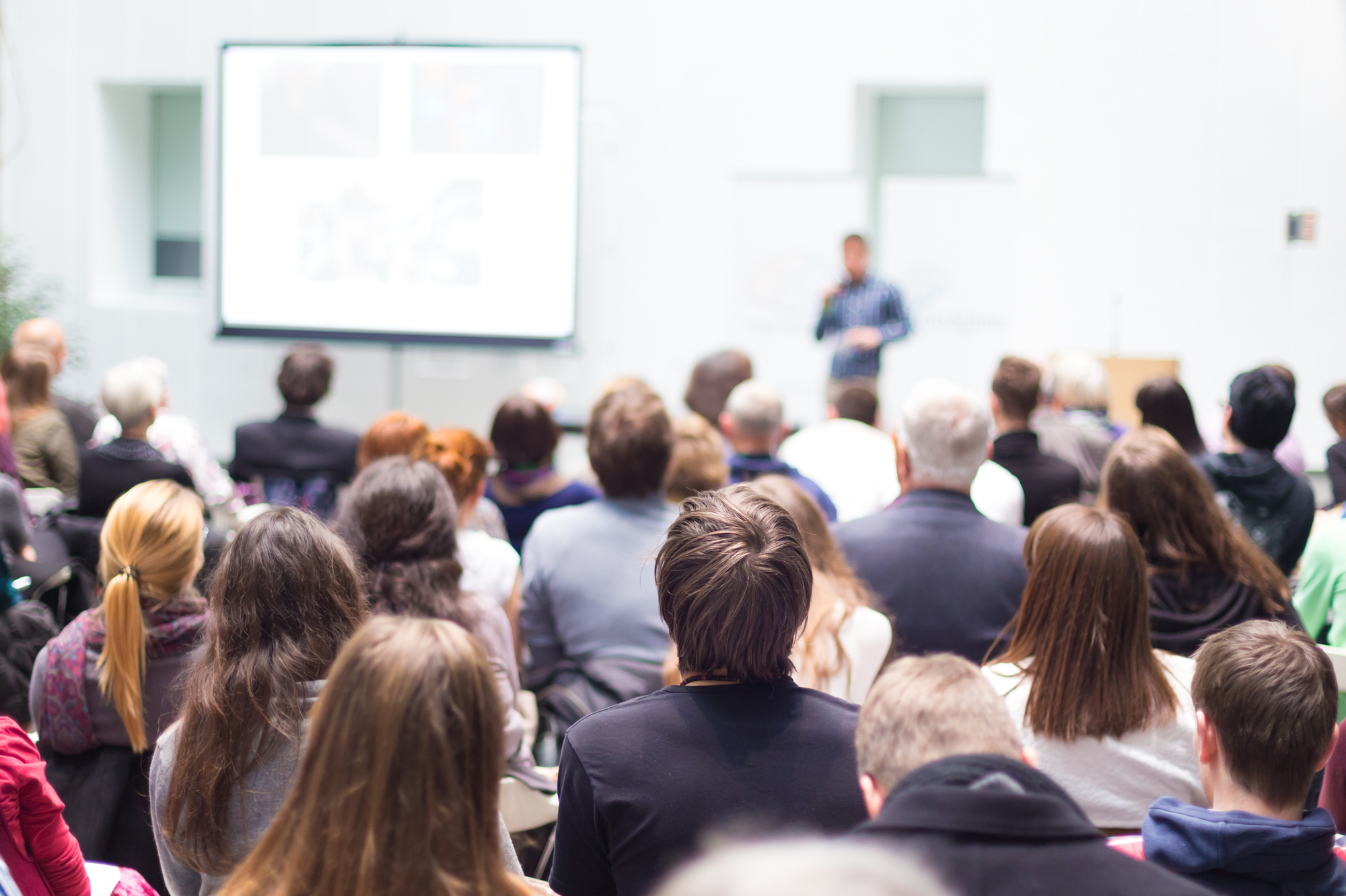 Speaker Giving a Talk at Business Meeting. Audience in the conference hall. Business and Entrepreneurship. Copy space on white board.